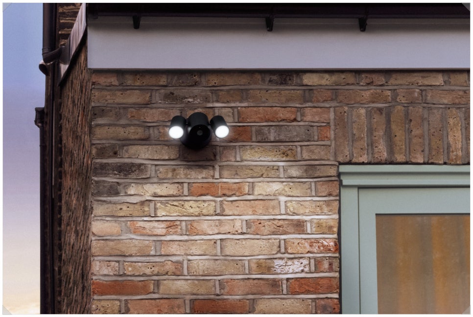 LG Floodlight Cam lighting a brick wall at dusk